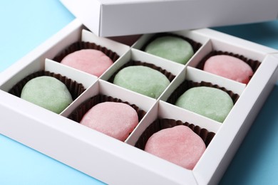 Many different delicious mochi in box on light blue background, closeup. Traditional Japanese dessert