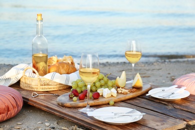 Photo of Food for picnic and white wine served on wooden pallet near river