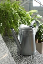 Photo of Watering can and home plants on stairs indoors