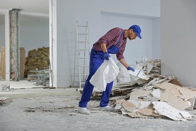 Construction worker with used building materials in room prepared for renovation