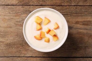 Delicious yogurt with fresh peach on wooden table, top view