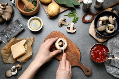Woman cutting mushroom at grey table, top view. Healthy cooking