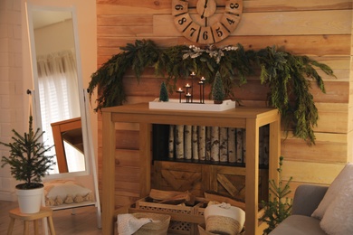 Cozy room interior with console table and conifer garland near wooden wall