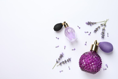 Photo of Bottles of natural perfume and lavender flowers on white background, top view. Cosmetic products