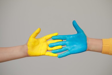 Little girl and boy with hands painted in Ukrainian flag colors on light grey background, closeup. Love Ukraine concept