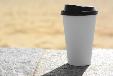 Photo of Takeaway coffee cup on stone surface outdoors. Space for text