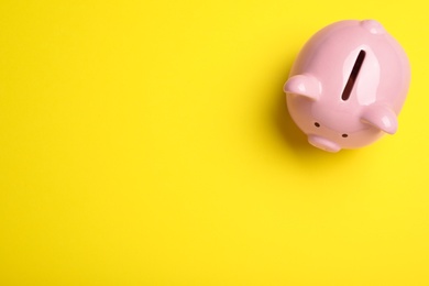 Top view of piggy bank on yellow background, space for text. Money savings