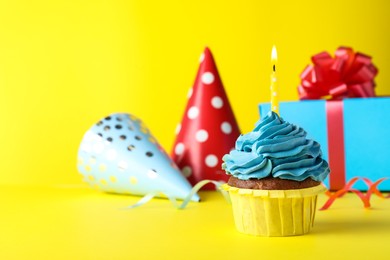 Delicious birthday cupcake with candle on yellow background, space for text