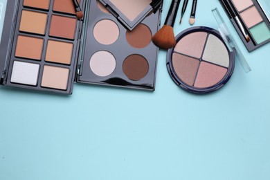 Photo of Colorful contouring palettes and brushes on light blue background, flat lay with space for text. Professional cosmetic product