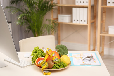 Nutritionist's workplace with fruits, vegetables, measuring tape and body fat calipers on table