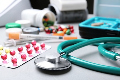 Stethoscope and pills on grey table. Medical objects