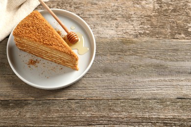 Photo of Slice of delicious layered honey cake served on wooden table, above view. Space for text