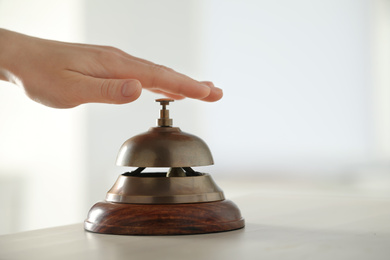 Man ringing hotel service bell at table indoors, closeup. Space for text
