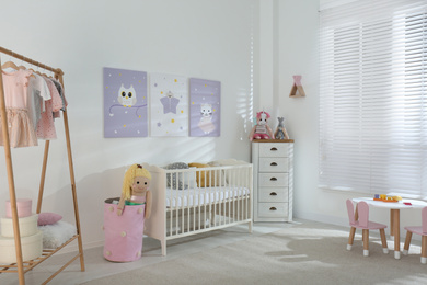 Baby room interior with cute posters, crib and clothing rack