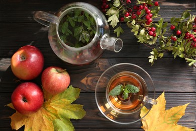 Photo of Hot tea, apples, dry leaves and viburnum on wooden table, flat lay. Autumn atmosphere