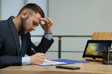 Forex trader working with tablet and documents at table in office