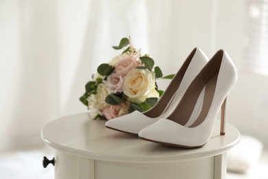 Pair of wedding high heel shoes and beautiful bouquet on white table, closeup