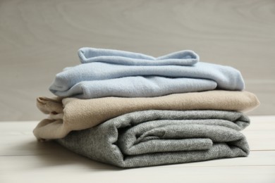 Photo of Stack of cashmere clothes on wooden table