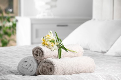 Terry towels with beautiful flowers on bed indoors, space for text