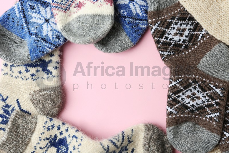 Frame made of knitted socks on pink background, flat lay with space for text. Winter clothes