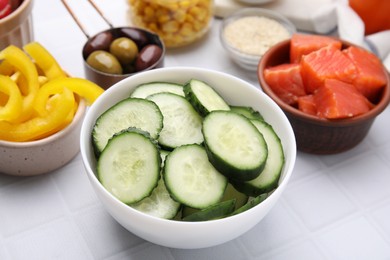 Photo of Ingredients for poke bowl on white checkered table, closeup