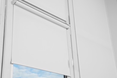 Window covered with white roller blinds indoors