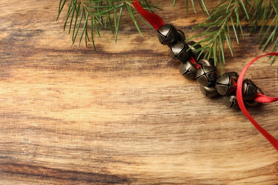 Metal sleigh bells on wooden table, flat lay. Space for text