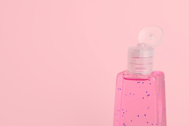 Photo of Bottle with antiseptic gel on pink background, closeup. Space for text
