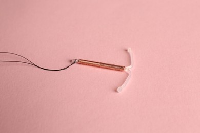 T-shaped intrauterine birth control device on pink background