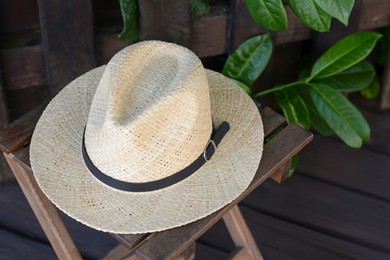Stylish hat on wooden stool near fence. Beach accessory