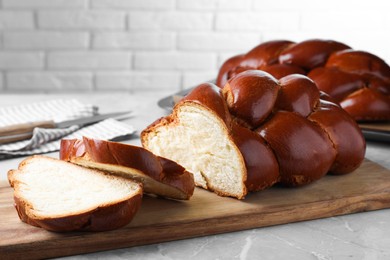 Photo of Cut homemade braided bread on grey table, closeup. Traditional Shabbat challah