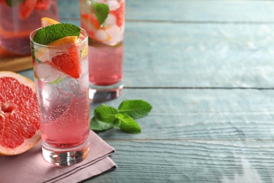 Photo of Delicious grapefruit lemonade with soda water and mint on blue wooden table, space for text. Fresh summer cocktail