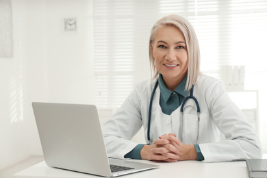 Portrait of mature female doctor in white coat at workplace