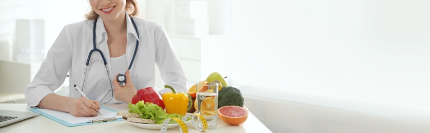 Nutritionist working at desk in office, closeup view with space for text. Banner design