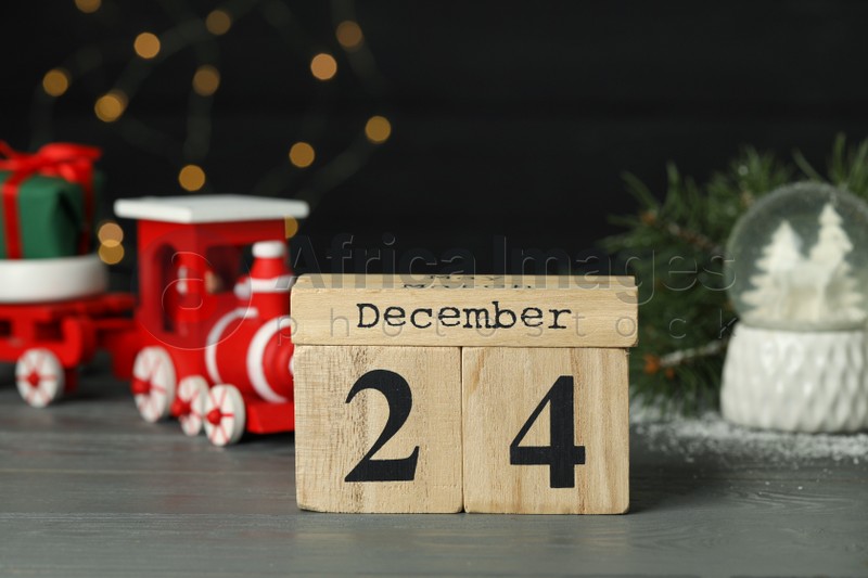 December 24 - Christmas Eve. Wooden block calendar and decor on table against blurred festive lights