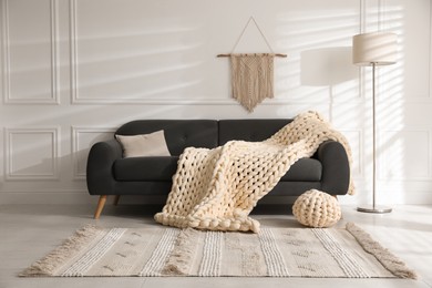 Soft chunky knit blanket on sofa in living room. Interior design