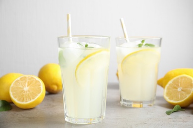 Glasses of cold lemonade on grey table