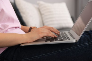 Woman with laptop on sofa at home, closeup