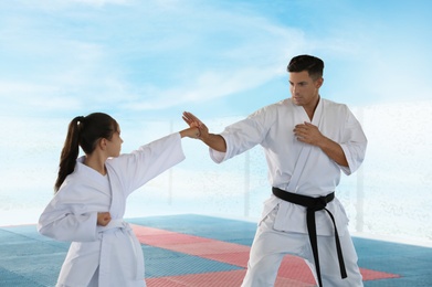 Girl practicing karate with coach on tatami outdoors