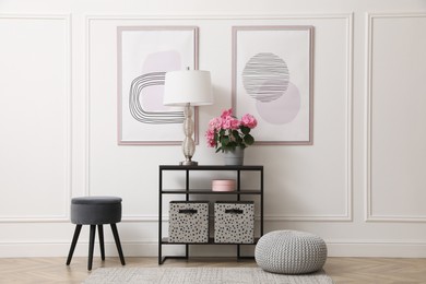 Console table with beautiful hydrangea flower and lamp near white wall in hallway. Interior design