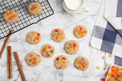 Unbaked cookies with candied fruits on white marble table, flat lay