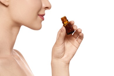 Photo of Young woman smelling essential oil on white background, closeup