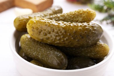 Photo of Bowl with tasty pickled cucumbers on table, closeup