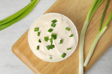 Fresh sour cream with onion on white wooden table, flat lay