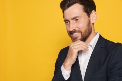 Photo of Smiling bearded man in suit looking away on orange background. Space for text