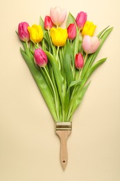 Photo of Brush with colorful tulips on beige background, top view. Creative concept