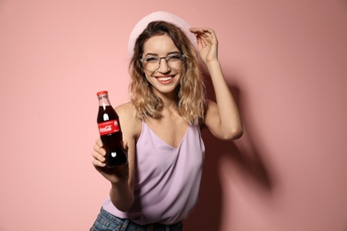 MYKOLAIV, UKRAINE - NOVEMBER 28, 2018: Young woman with bottle of Coca-Cola on color background