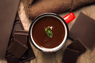 Mug of delicious hot chocolate with fresh mint leaves on wooden table, flat lay