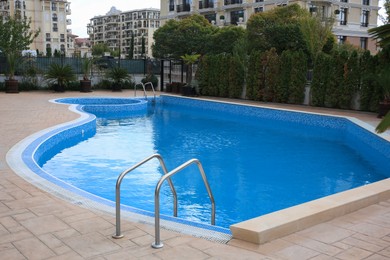 Photo of Pool with clean water and grab bars outdoors
