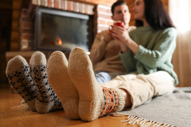 Lovely couple with delicious cocoa near fireplace at home, focus on feet. Winter vacation